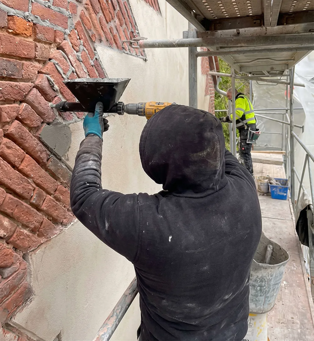 Un ouvrier en train d'appliquer du ciment sur un mur en briques